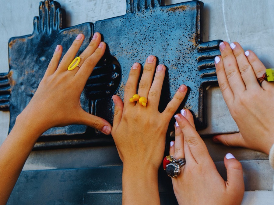 Hands touching a moulded clay panel in an art workshop.